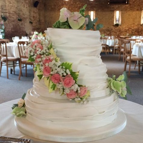 A 3 tier vintage ruffle wedding cake with fresh flowers supplied by the bride